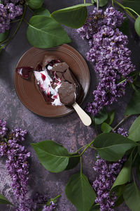 Melted raspberry ice cream in chocolate on a wooden stick on a dark table