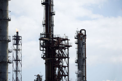 Low angle view of oil refinery  against sky