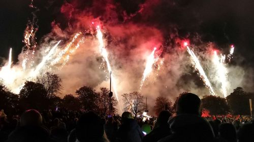 People looking at firework display at night