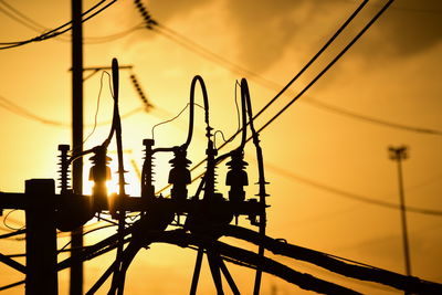 Low angle view of silhouette electricity pylon against sky during sunset