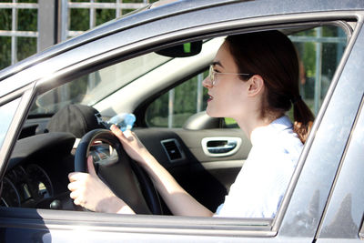 Side view of woman sitting in car