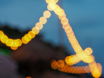Close-up of illuminated yellow lights against sky at night