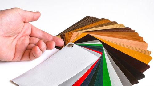 Close-up of hand holding book against white background