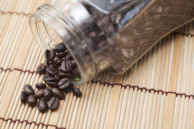 Roasted coffee beans spilling from jar on place mat