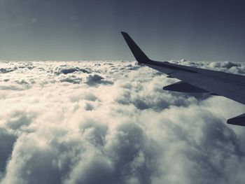 Cropped image of airplane against cloudy sky