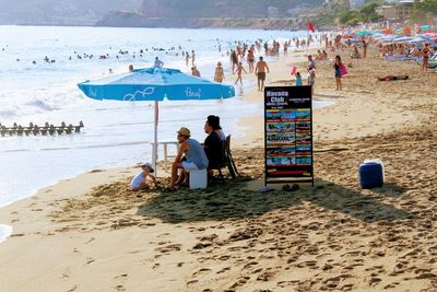 People sitting on beach against sky