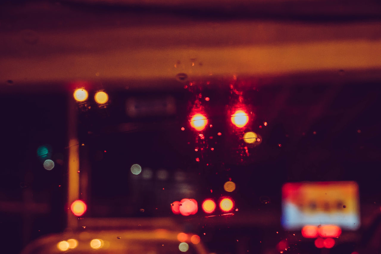 DEFOCUSED IMAGE OF ILLUMINATED CITY SEEN THROUGH WET GLASS