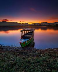 Boat moored in lake against sky during sunset