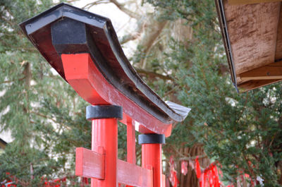 Low angle view of red telephone pole against trees