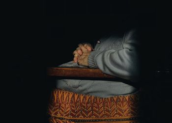 Portrait of young man sitting on seat against black background