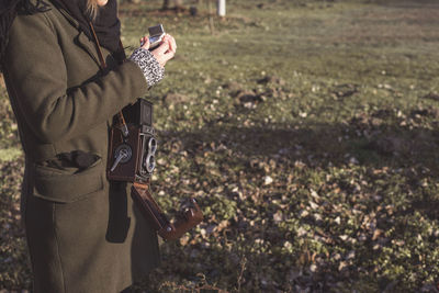 Midsection of woman with antique camera standing on grass field