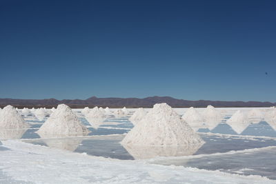 Salt stacks on flats against clear blue sky