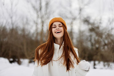 Portrait of young woman standing against trees during winter