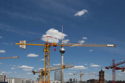 Fernsehturm and cranes against sky