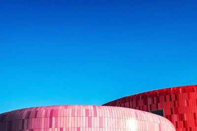 Low angle view of red building against clear blue sky