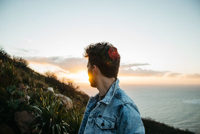 Man looking at sea against sky during sunset