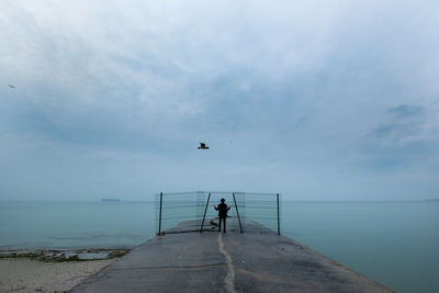 Woman standing behind bars near the sea