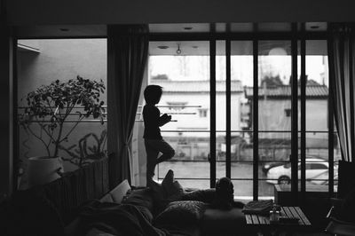 Rear view of boy standing by window