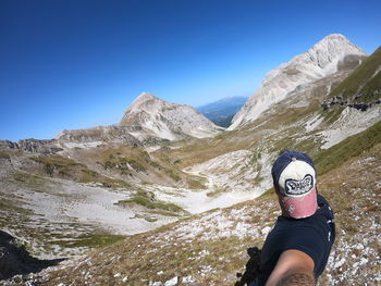 Low section of man against mountains against clear blue sky