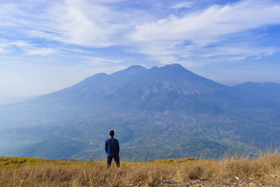 Rear view of man looking at mountains against sky