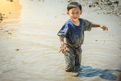 Portrait of smiling boy playing on mud outdoors