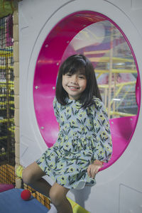 Portrait of smiling innocent girl sitting in slide