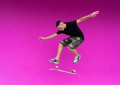 Full length of woman running against pink background