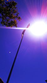 Low angle view of sun shining through blue sky