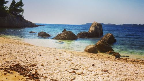 Rocks on beach against clear sky