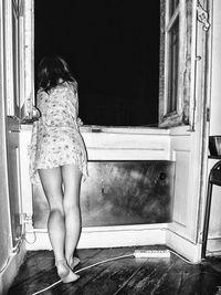 Rear view of woman standing against door at home