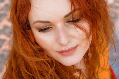 Close-up portrait young caucasian woman with red curly hair in red coat in wind person