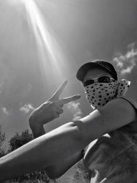 Low angle view of man holding sunglasses against sky