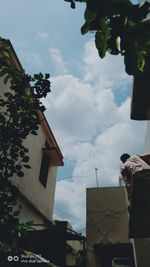 Low angle view of hand holding building against sky