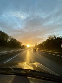 Road seen through car windshield during sunset