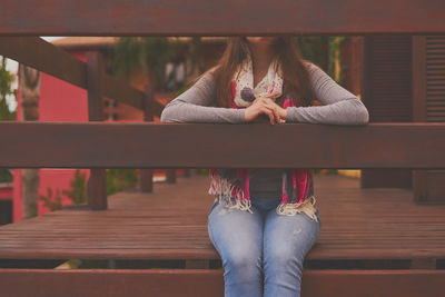 Midsection of woman sitting on balcony while sitting at railing