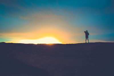 Silhouette man standing on mountain against sky during sunset