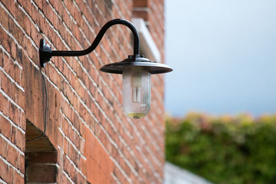 Low angle view of lighting equipment on brick wall against clear sky