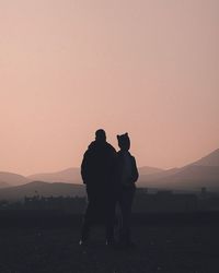 Silhouette men standing on mountain against sky during sunset