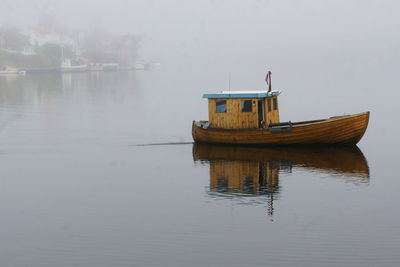 Wooden boat moored at river on foggy morning