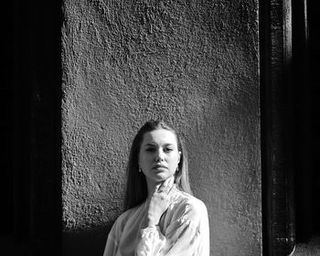 Portrait of beautiful young woman standing against wall