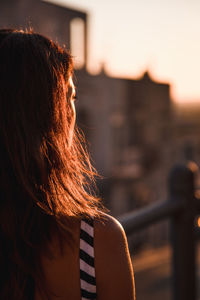 Rear view of woman standing against sky during sunset