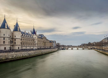 Buildings by river against sky