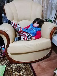 High angle view of cute girl resting on sofa