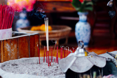 Close-up of lit candles on table in temple