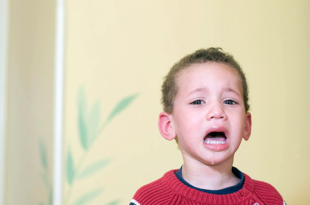 PORTRAIT OF CUTE BOY AGAINST WALL AT HOME