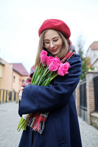 Young french millennial girl in beret and coat with tulips in hands