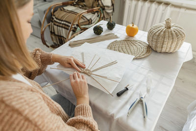 Over shoulder view of woman weaving basket