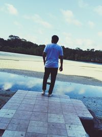 Rear view of man standing against cloudy sky