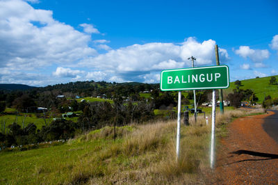 Road sign on field against sky