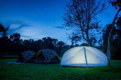 Tent on field against trees and blue sky